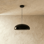 Clérachic glossy black dome pendant hanging from a black ceiling canopy, shown with the light off against plaster.