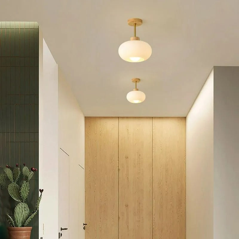 Two Clérachic white dome ceiling lights running down a hallway with green tiling and oak panelled doors.