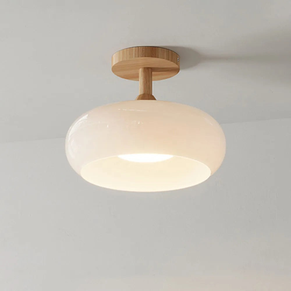 Clérachic dome ceiling light in glossy white, semi-flush on its wood canopy with light pooling from the open underside.