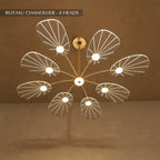 Clérachic leaf-shaped chandelier, the 8-head version, its acrylic panels glowing warm against a brown plaster wall.