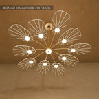 Clérachic leaf-shaped chandelier, the 10-head version, its acrylic panels glowing warm against a brown plaster wall.