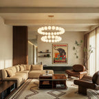Clérachic two-tier round chandelier of glowing opal globes over a low coffee table and sofa in a beamed living room.