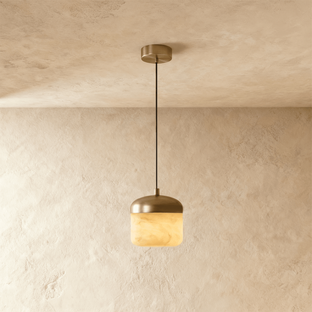 Clérachic alabaster pendant light, a single glowing stone drum shade under a brass dome, hung from a plaster ceiling.