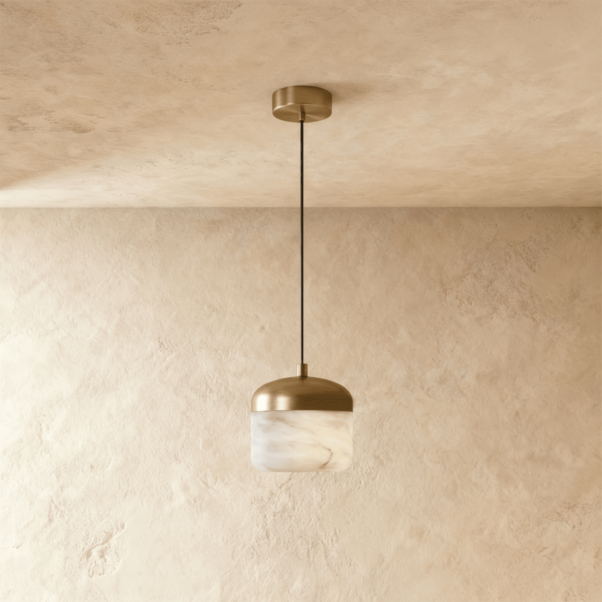 Clérachic alabaster pendant light, unlit, its veined stone drum shade sitting beneath a brushed brass canopy.