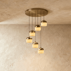 Clérachic alabaster pendant light in the 6-light cluster, glowing stone shades cascading from a round brass canopy.