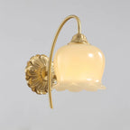 Front-on view of this Clérachic brass wall light, its cream glass bell shade hanging from a tall curved arm.