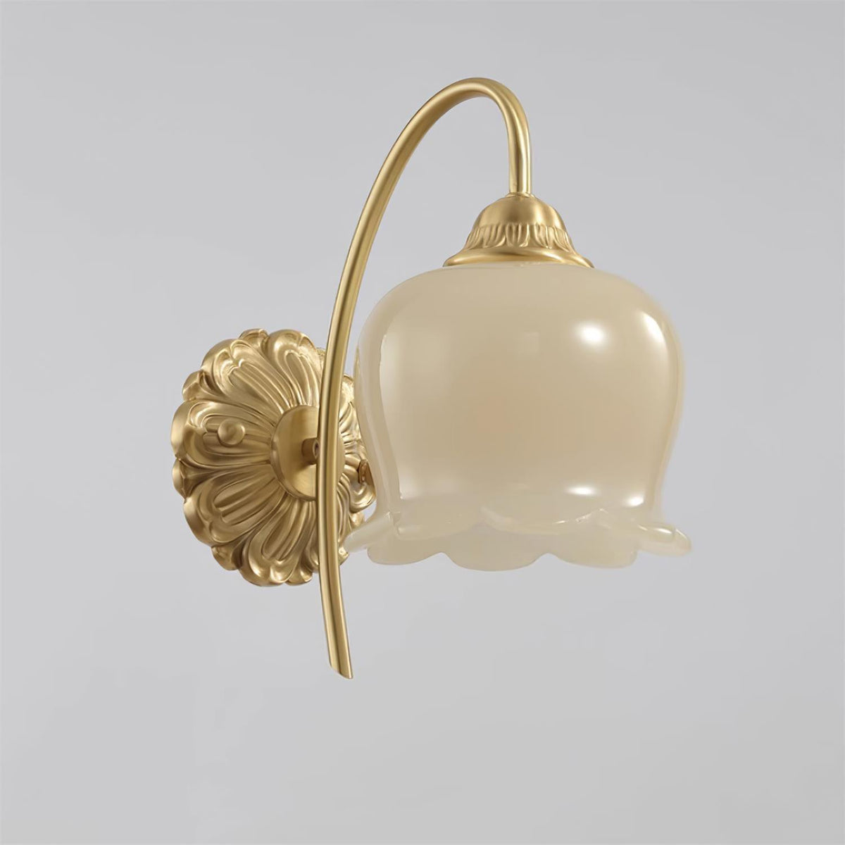 Clérachic brass wall light with a frilled cream glass shade and ornate round back plate, on a plain grey background.