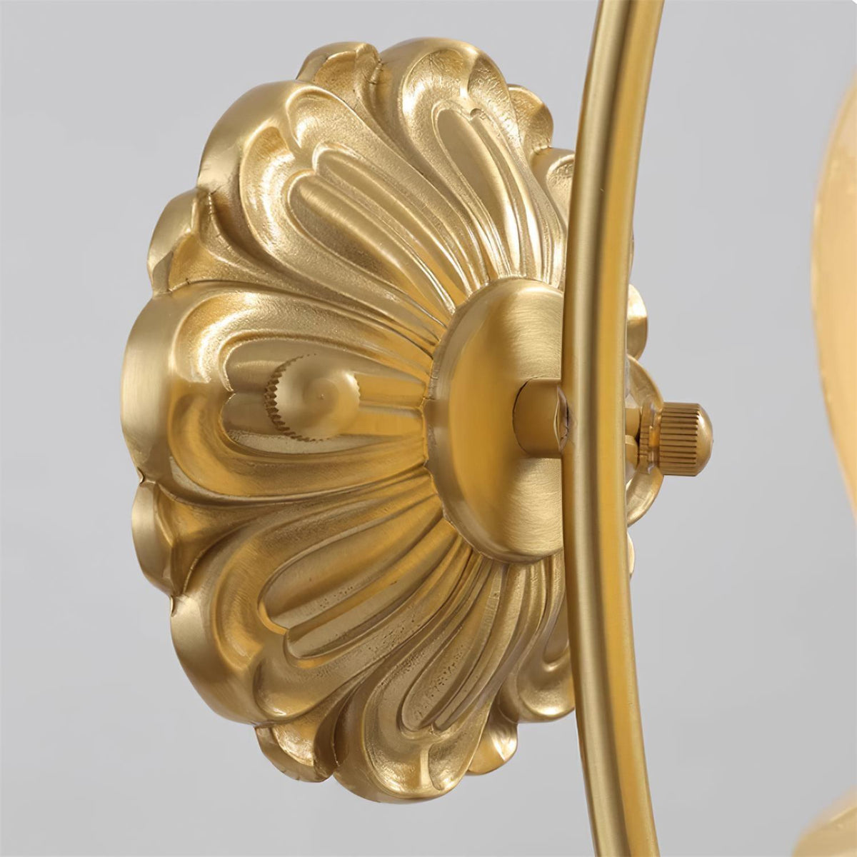 Close view of the embossed brass back plate and curved arm joint on this Clérachic wall light.