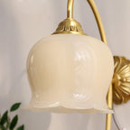 Close view of the cream glass bell and the ridged brass cap where it meets the arm on this Clérachic wall light.