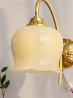 Close view of the ribbed cream glass shade and brass cap on this Clérachic wall light, with the cable showing at the back.