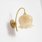 Angled view of the unlit Clérachic wall light, with the cream glass bell and ridged brass cap in clear detail.