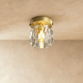 Clérachic flush ceiling light with a faceted crystal shade and a brushed gold plate, lit on a plaster ceiling.