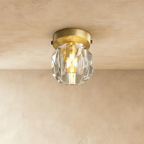 Clérachic flush ceiling light with a faceted crystal shade and a brushed gold plate, lit on a plaster ceiling.