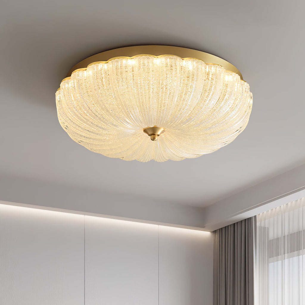 Low-angle view of the lit ribbed glass shade and gold rim of this Clérachic ceiling light, with a soft cove light along the wall.