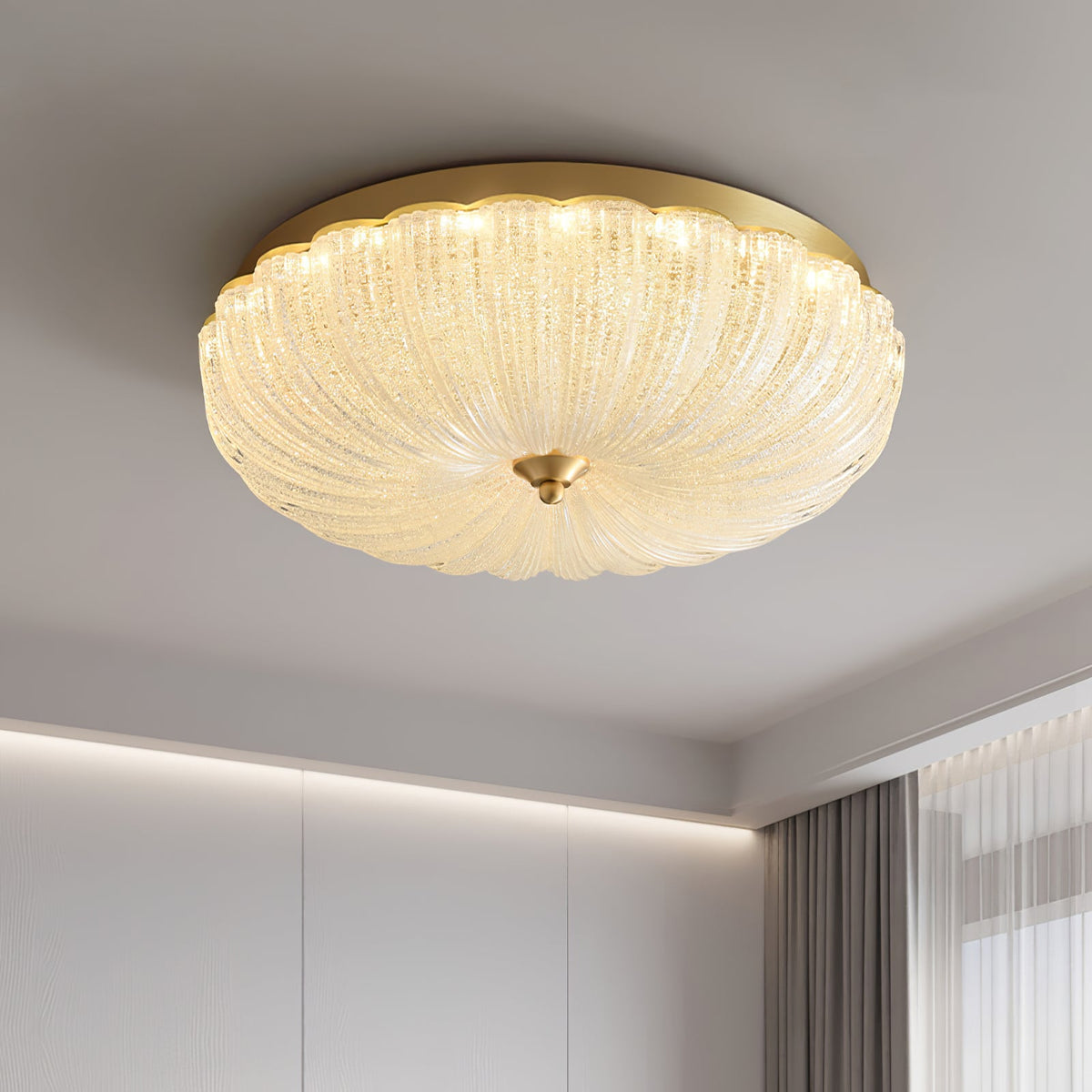 Low-angle view of the lit ribbed glass shade and gold rim of this Clérachic ceiling light, with a soft cove light along the wall.
