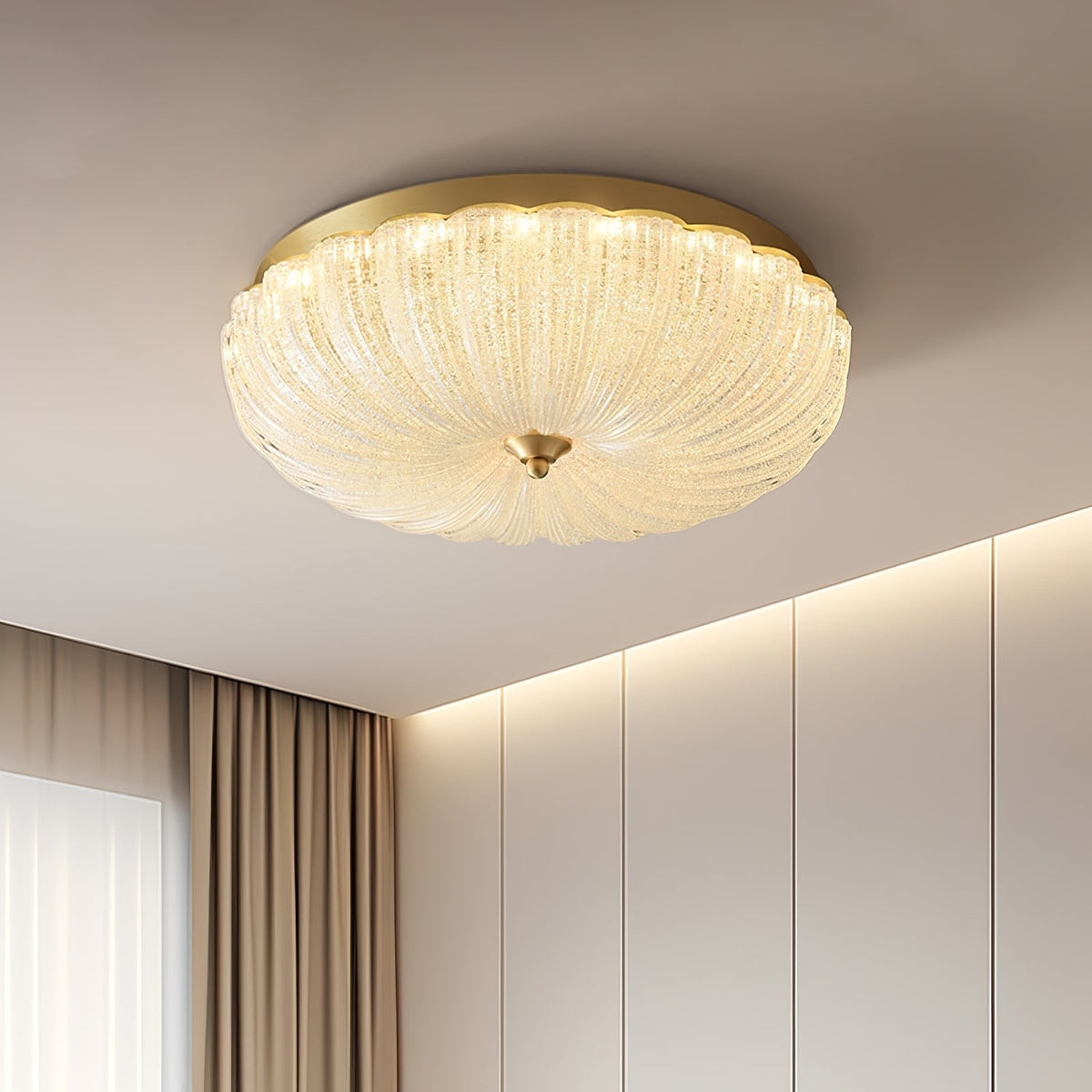 Clérachic ceiling light seen from the side, its textured glass shade and gold rim lit above a wall of cream panels and curtains.