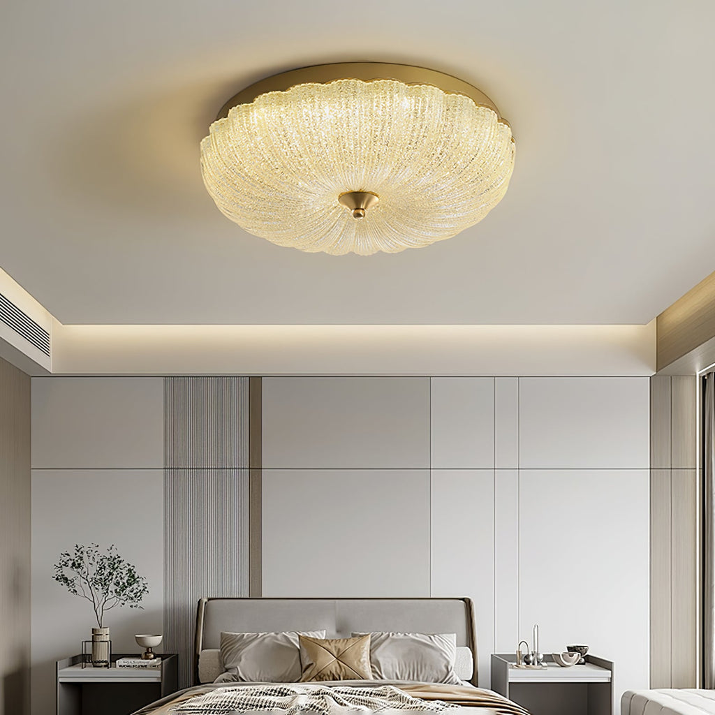 Clérachic ceiling light glowing above a calm bedroom with a cream headboard, panelled wall and a vase of branches on a bedside table.