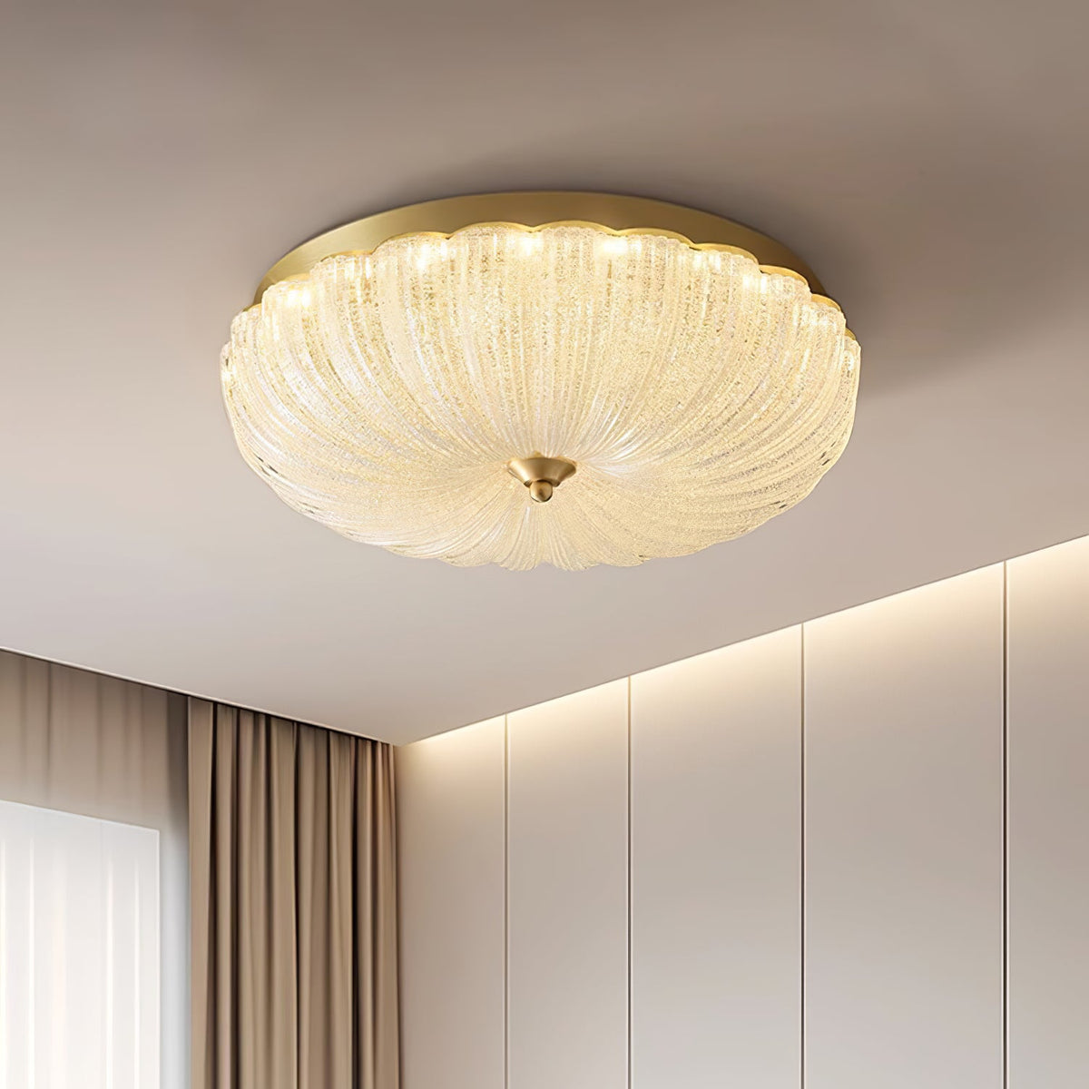 Close low view of the ribbed, sparkling glass shade and gold backplate of this Clérachic ceiling light beside a cove-lit wall.