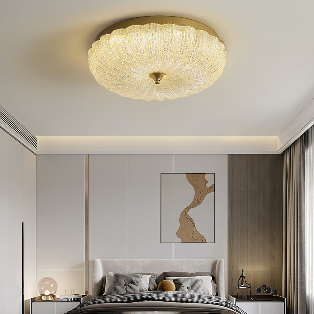 Wide Clérachic flush ceiling light above a bedroom with a grey bed, a wall painting and a cove-lit ceiling edge.