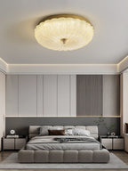 Clérachic flush ceiling light above a bedroom with a low grey upholstered bed, a slatted panel and a pale rug.