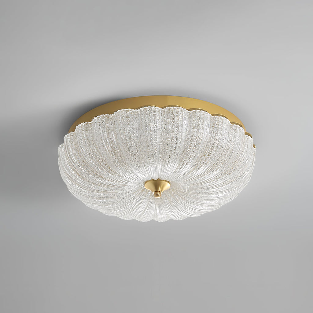 Unlit Clérachic ceiling light with a clear, ribbed glass shade, a gold backplate and a brass finial, on a plain grey backdrop.