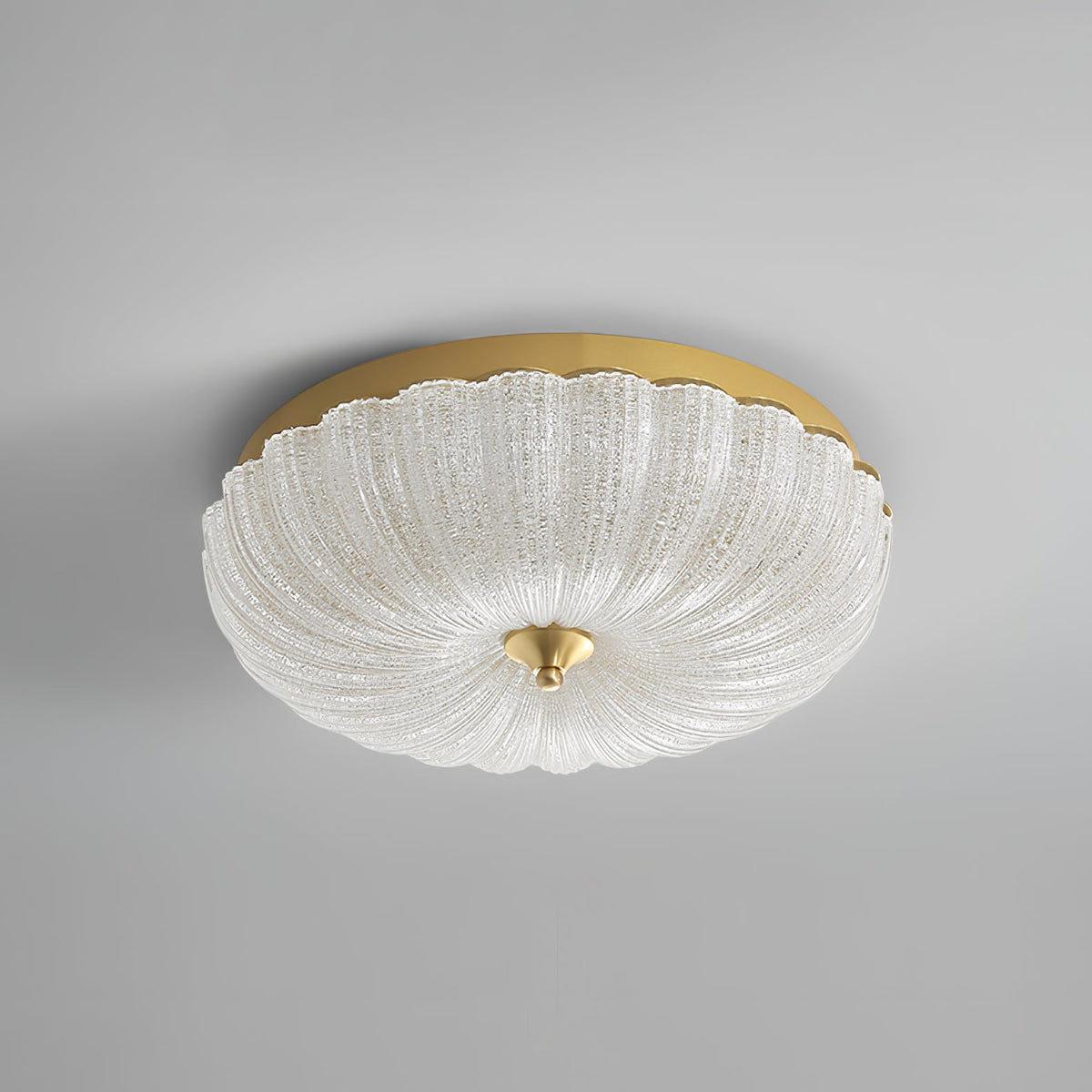 Unlit Clérachic ceiling light with a clear, ribbed glass shade, a gold backplate and a brass finial, on a plain grey backdrop.