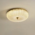 Warm-lit Clérachic ceiling light with a ribbed glass shade and a gold rim on a soft beige backdrop.