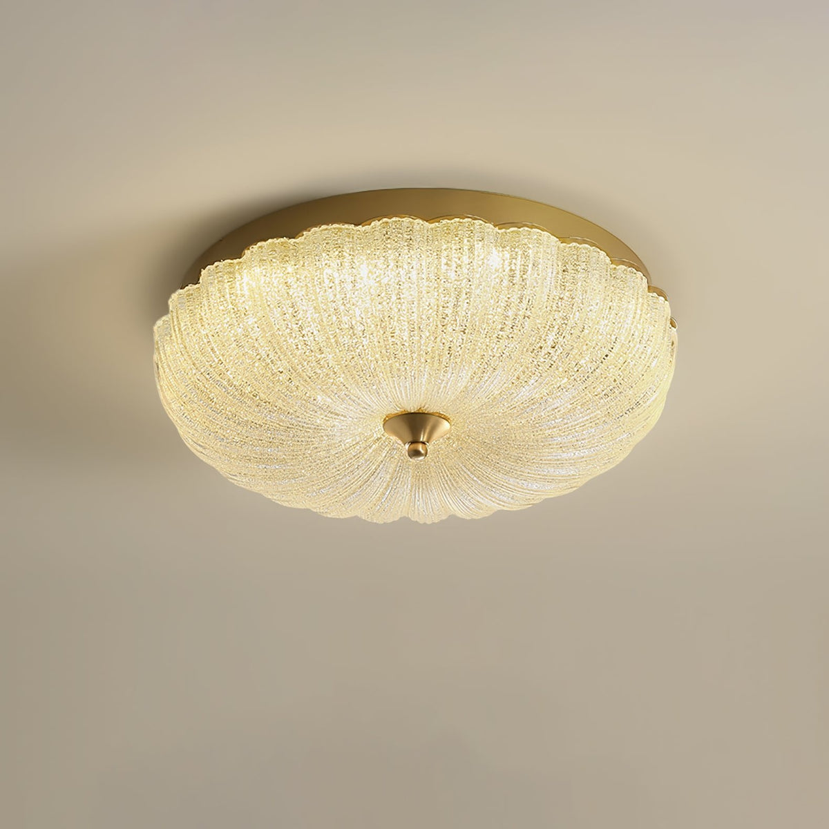 Warm-lit Clérachic ceiling light with a ribbed glass shade and a gold rim on a soft beige backdrop.