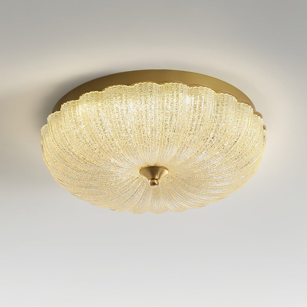 Lit Clérachic ceiling light with a golden-glowing ribbed glass shade, seen from slightly below on a pale grey backdrop.