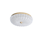 Unlit Clérachic ceiling light with a clear ribbed glass shade, a gold backplate and a brass finial, on a plain white backdrop.