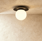 Clérachic's ceiling light in black, a round opal glass globe set beneath a black disc mount overhead.