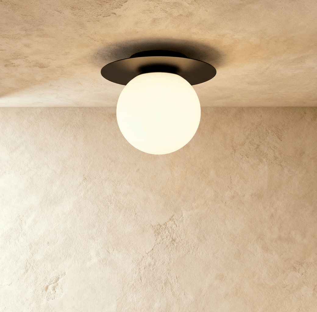 Clérachic's ceiling light in black, a round opal glass globe set beneath a black disc mount overhead.