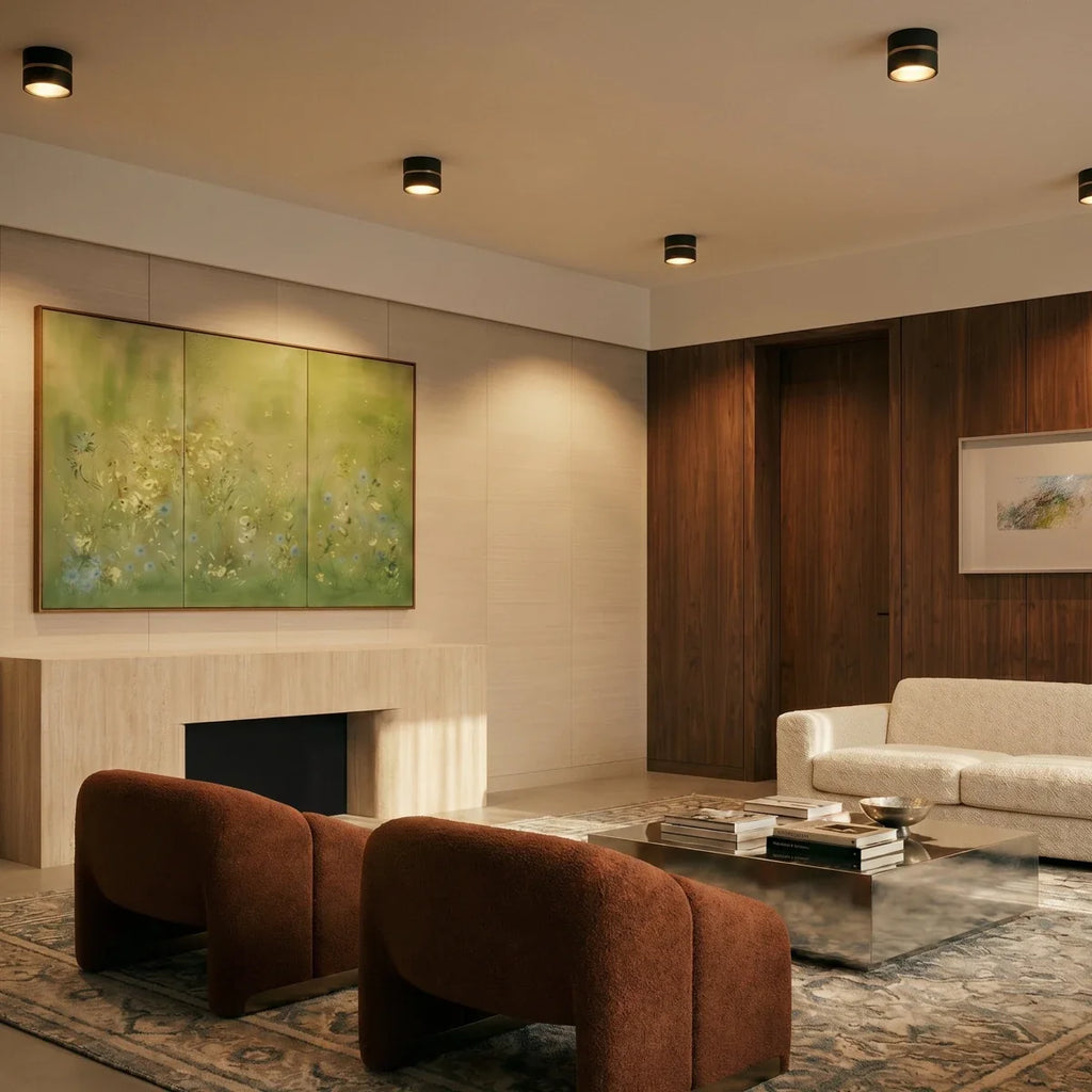 Clérachic black surface-mounted downlights spaced across a living room ceiling, lighting a framed landscape painting.