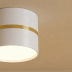Clérachic surface-mounted downlight in close detail, showing the white cylinder body and brushed brass accent ring.