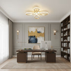The Clérachic gold ceiling light above a dark wooden executive desk, with a gold-and-blue canvas and a tall bookcase behind.