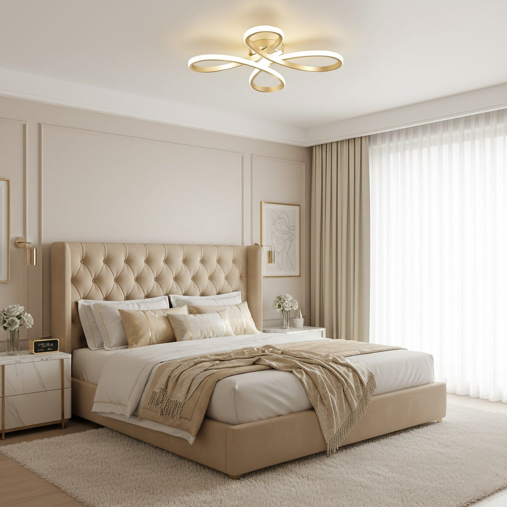 Gold Clérachic ceiling light above a bedroom with a tufted beige headboard, a knitted throw and long cream curtains.