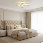 Gold Clérachic ceiling light above a bedroom with a tufted beige headboard, a knitted throw and long cream curtains.