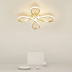 Close view of the lit Clérachic ceiling light on a cream ceiling, its four gold loops giving off a soft warm glow.