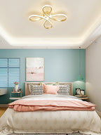 Clérachic gold ceiling light above a bedroom with a teal wall, a pink blanket and a recessed cove of warm ceiling light.