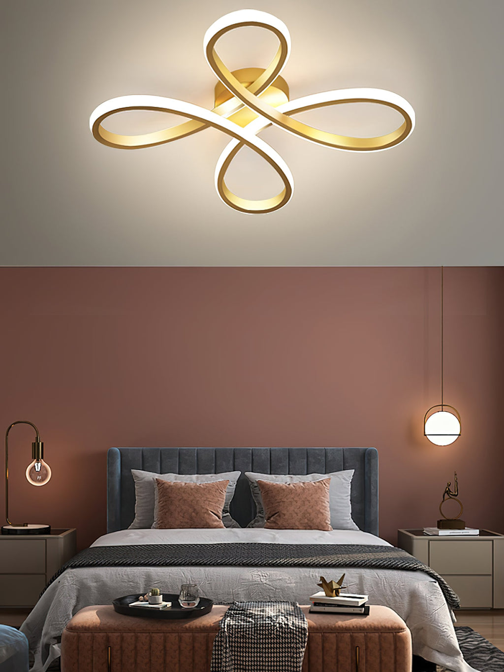 Close view of the Clérachic gold ceiling light above a bedroom with a terracotta wall, a blue-grey headboard and two small pendants.