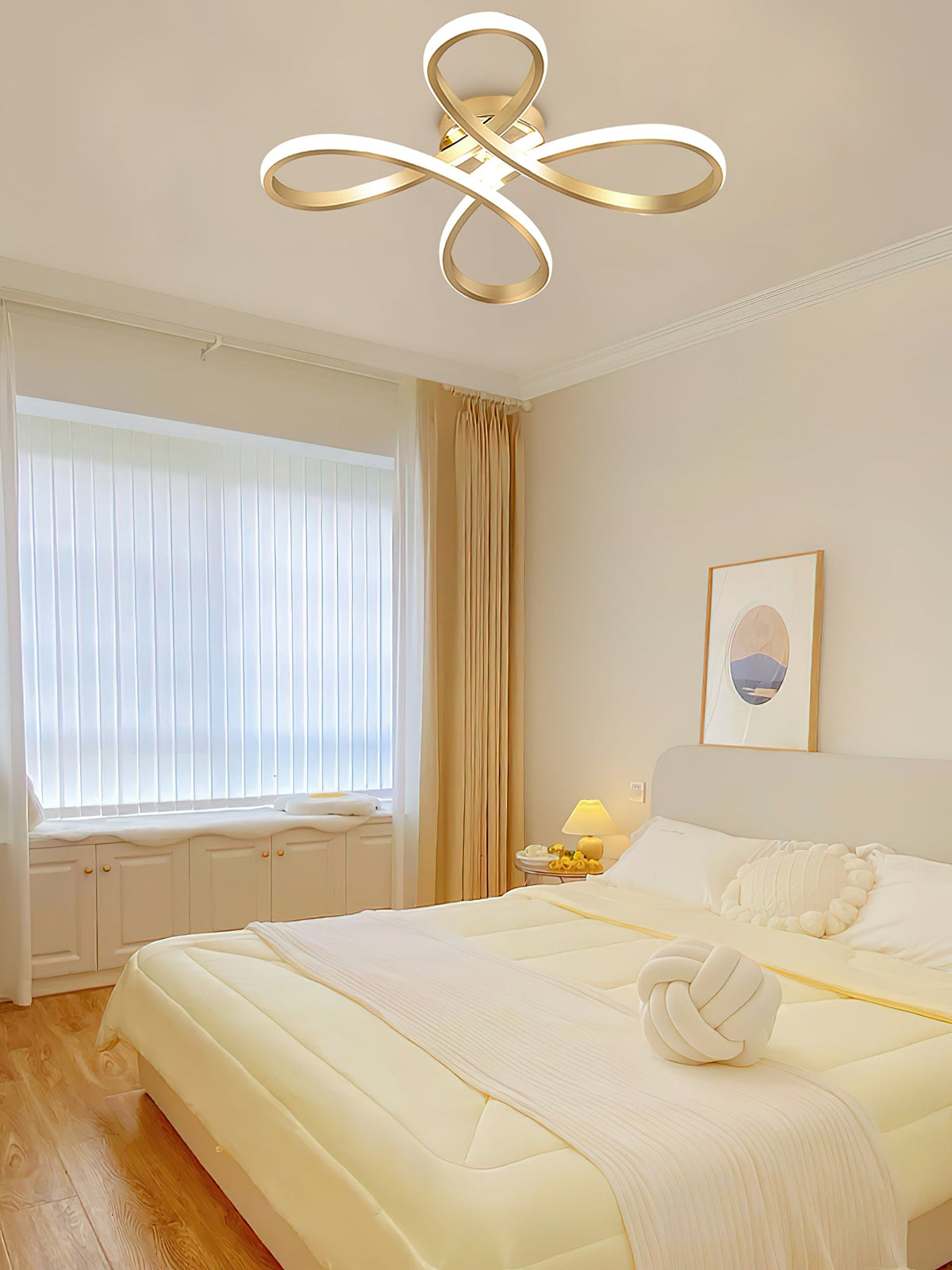 Gold Clérachic ceiling light above a bedroom with a pale bed, a knotted cushion, a window with blinds and gold curtains.