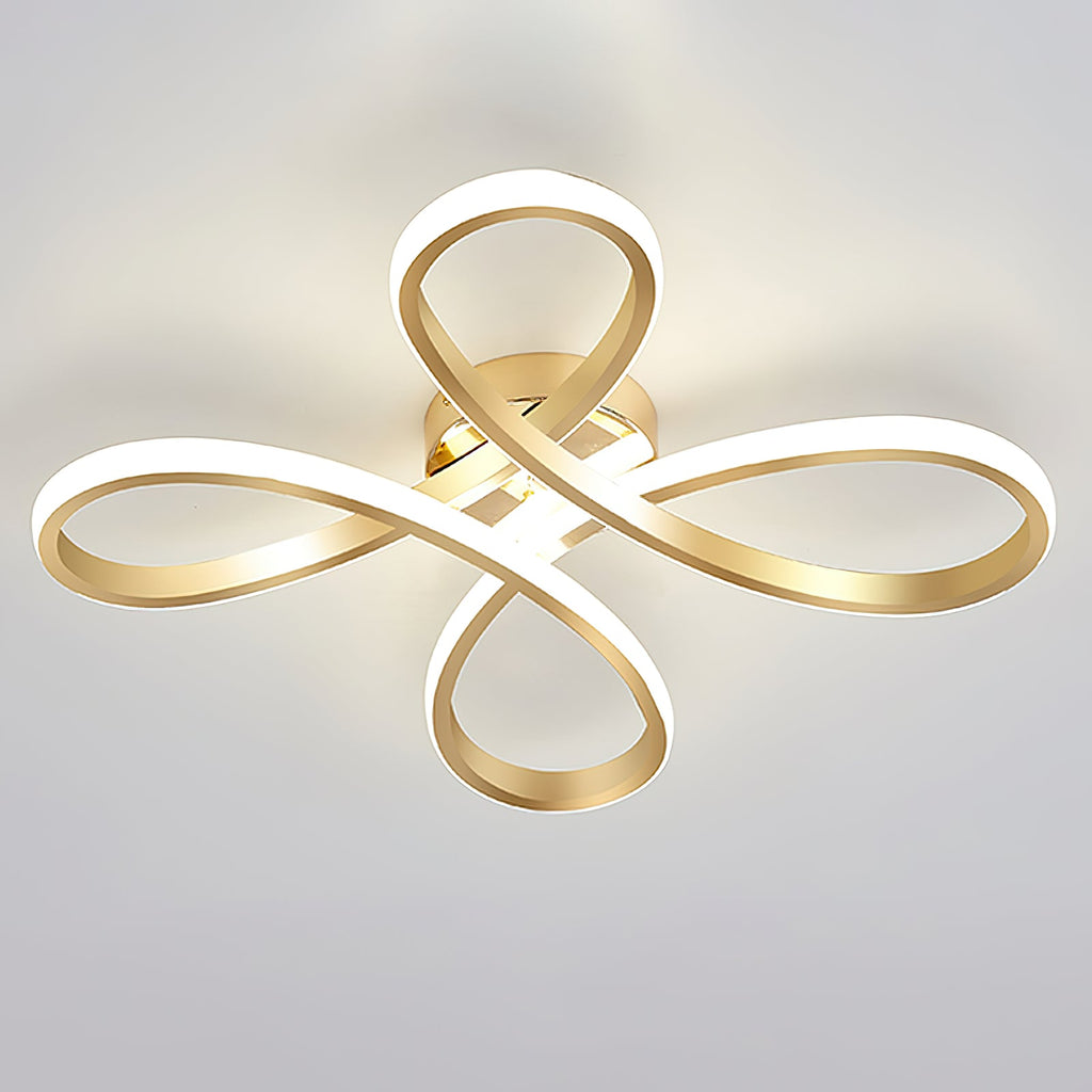 Clérachic gold ceiling light from below, its four loops lit, seen against a pale grey-blue ceiling.