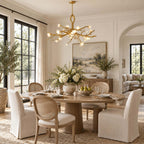 The Clérachic chandelier hangs over a round pale-wood dining table with cane-backed chairs, beside tall black-framed windows.