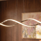 Close-up of the Clérachic chandelier's chrome twisted ribbon glowing warmly against a wood-panelled wall and painting.