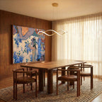 A Clérachic chandelier in gold lights a dining table beneath sheer curtains and a bold painting.