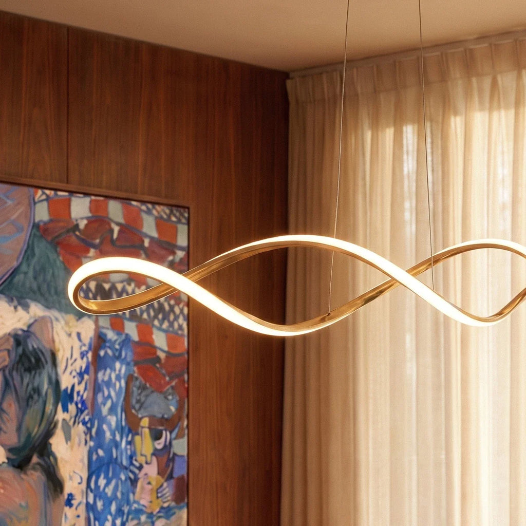 Close-up of the Clérachic chandelier's gold ribbon glowing beside a colourful framed painting.