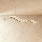 This Clérachic wave chandelier hangs in a long sculptural curve against a warm sandy plaster backdrop.
