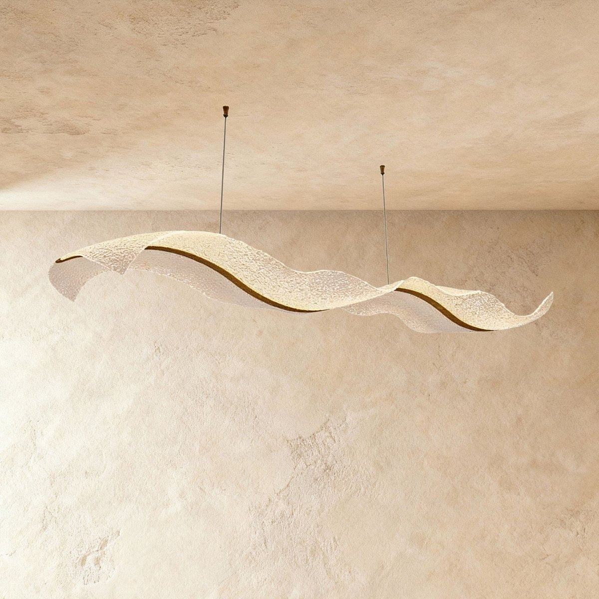 This Clérachic wave chandelier hangs in a long sculptural curve against a warm sandy plaster backdrop.