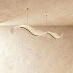 Clérachic's undulating acrylic chandelier forms two connected waves, lit softly on a plaster ceiling.