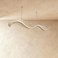 This Clérachic ribbon chandelier curls into a flowing double wave, its surface catching warm ambient light.